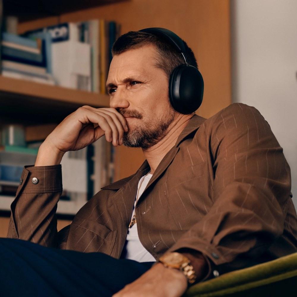 Férfi felhasználó egy fekete Sonos Ace fejhallgatót visel egy székben ülve.